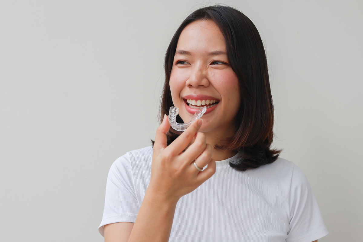 Woman applying a clear retainer to her smile